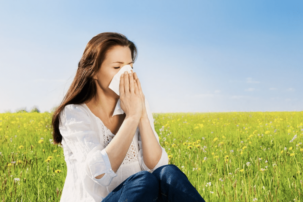 Femme souffrant d'allergies saisonnières dans un champ illustrant des remèdes naturels contre le rhume des foins