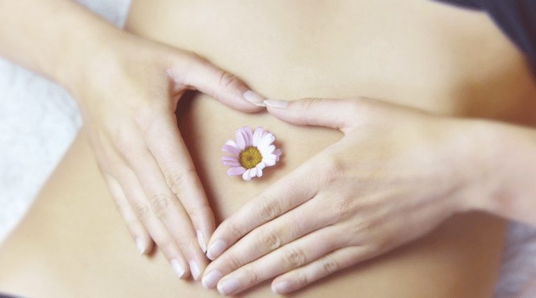 Personne tenant son ventre avec une fleur illustrant des remèdes naturels contre les maux de ventre et les troubles digestifs