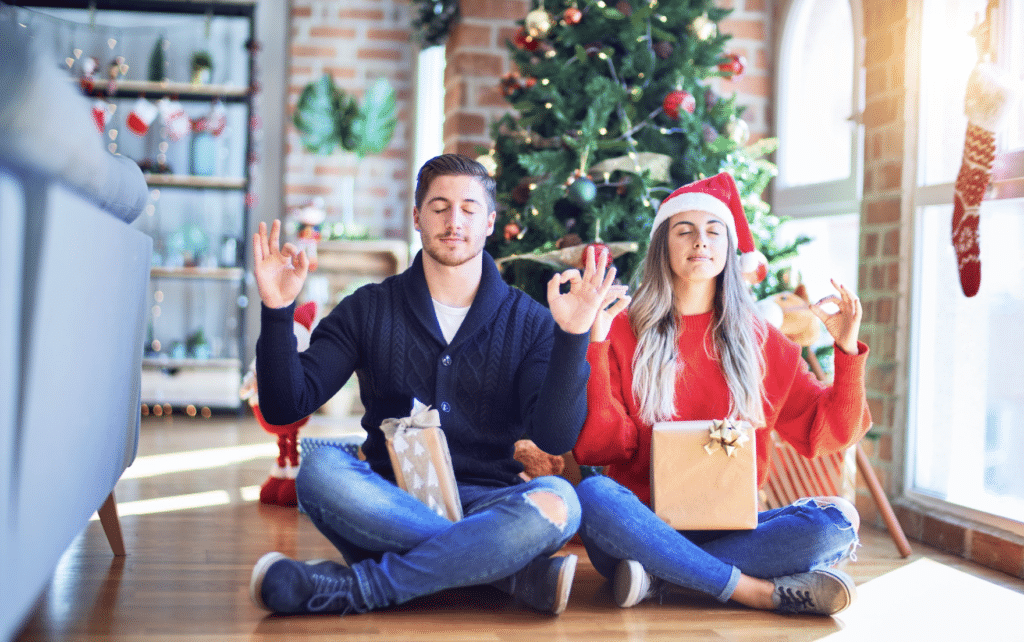 Couple détendu méditant devant un sapin de Noël pour illustrer la gestion du stress pendant les fêtes de fin d'année