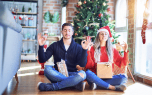Couple détendu méditant devant un sapin de Noël pour illustrer la gestion du stress pendant les fêtes de fin d'année