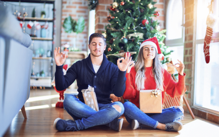 Couple détendu méditant devant un sapin de Noël pour illustrer la gestion du stress pendant les fêtes de fin d'année